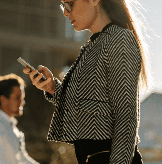 Businesswoman-using-mobile-phone-while-walking-on-street-to-offi